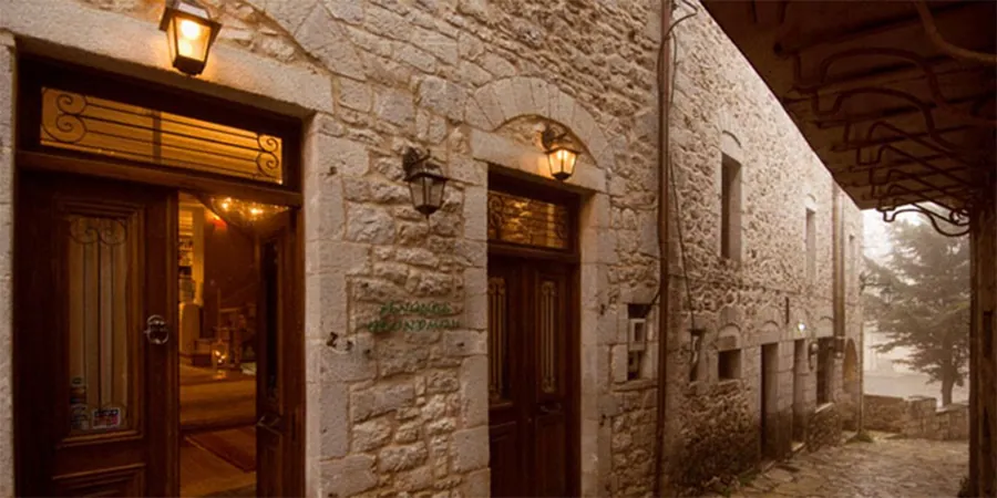 Η πέτρινη είσοδος του ξενώνα με τα ξύλινα πορτόφυλλα